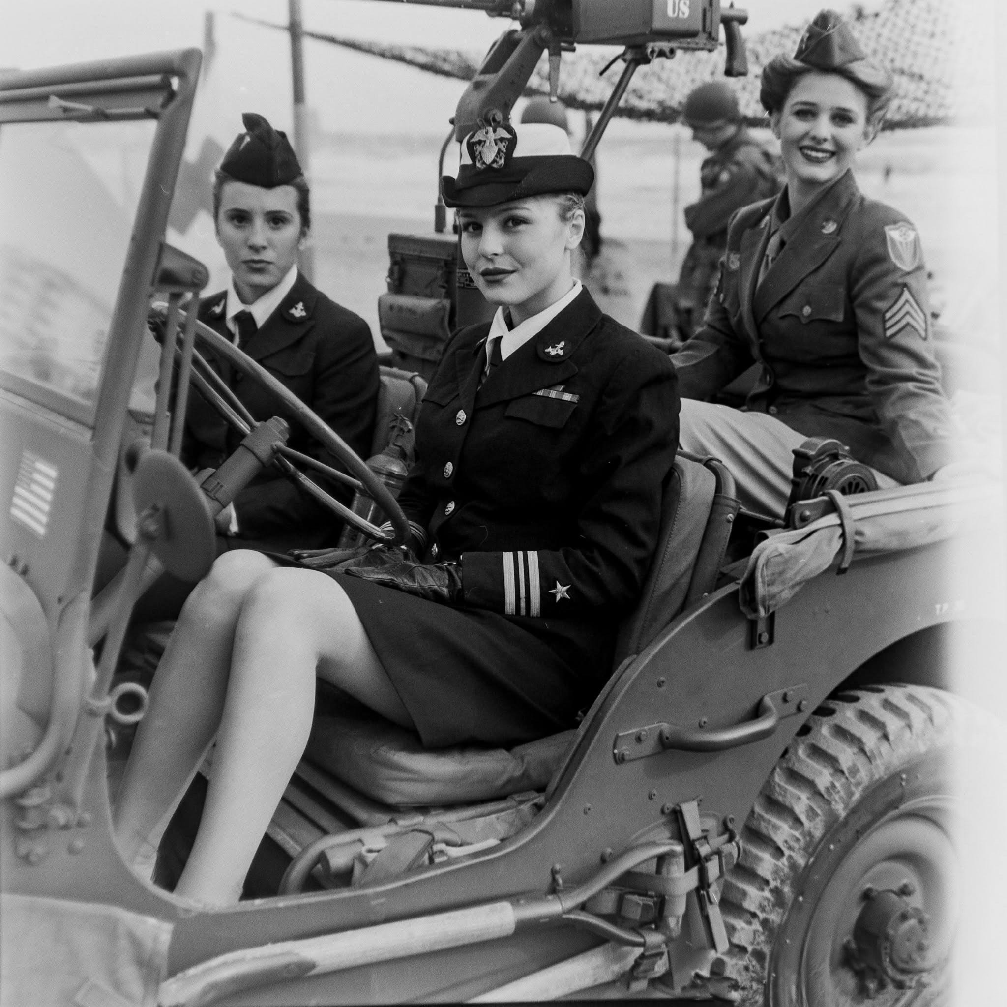 Tre donne in uniforme militare sedute su una jeep d'epoca in bianco e nero