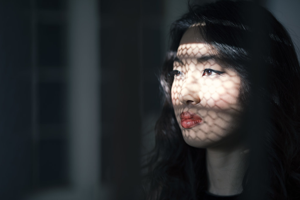 Ritratto femminile attraversato da un disegno di luce e ombra