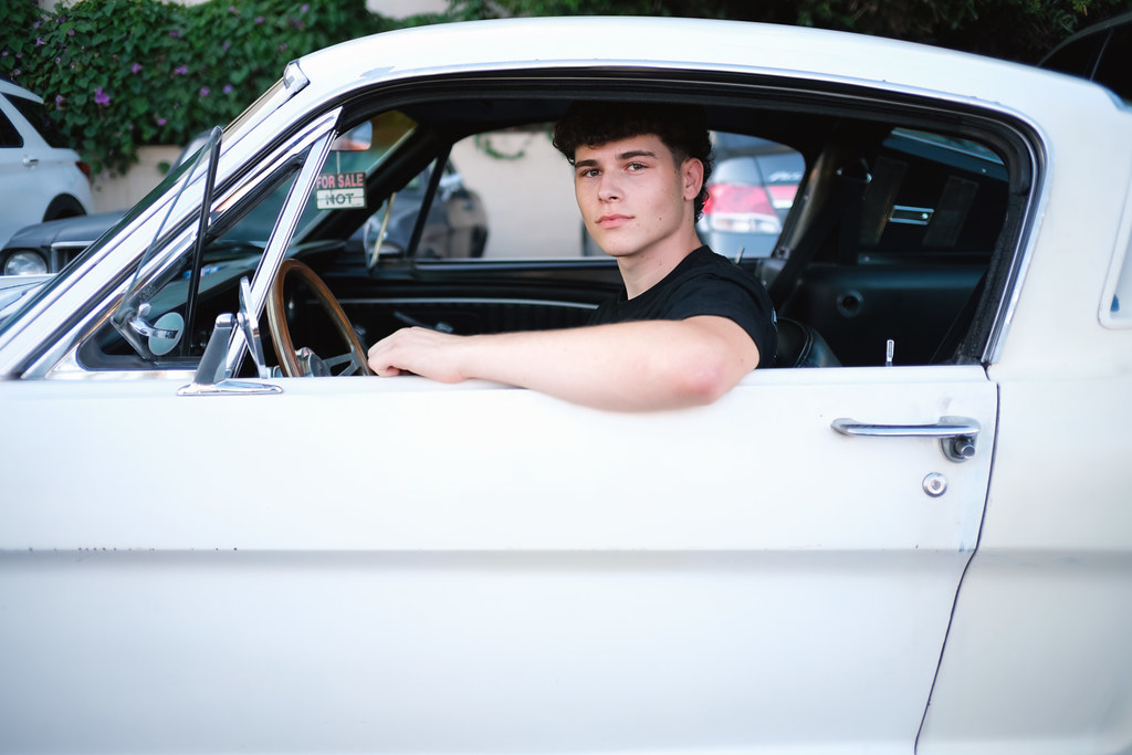 Ritratto di un ragazzo al volante di un'auto americana d'epoca