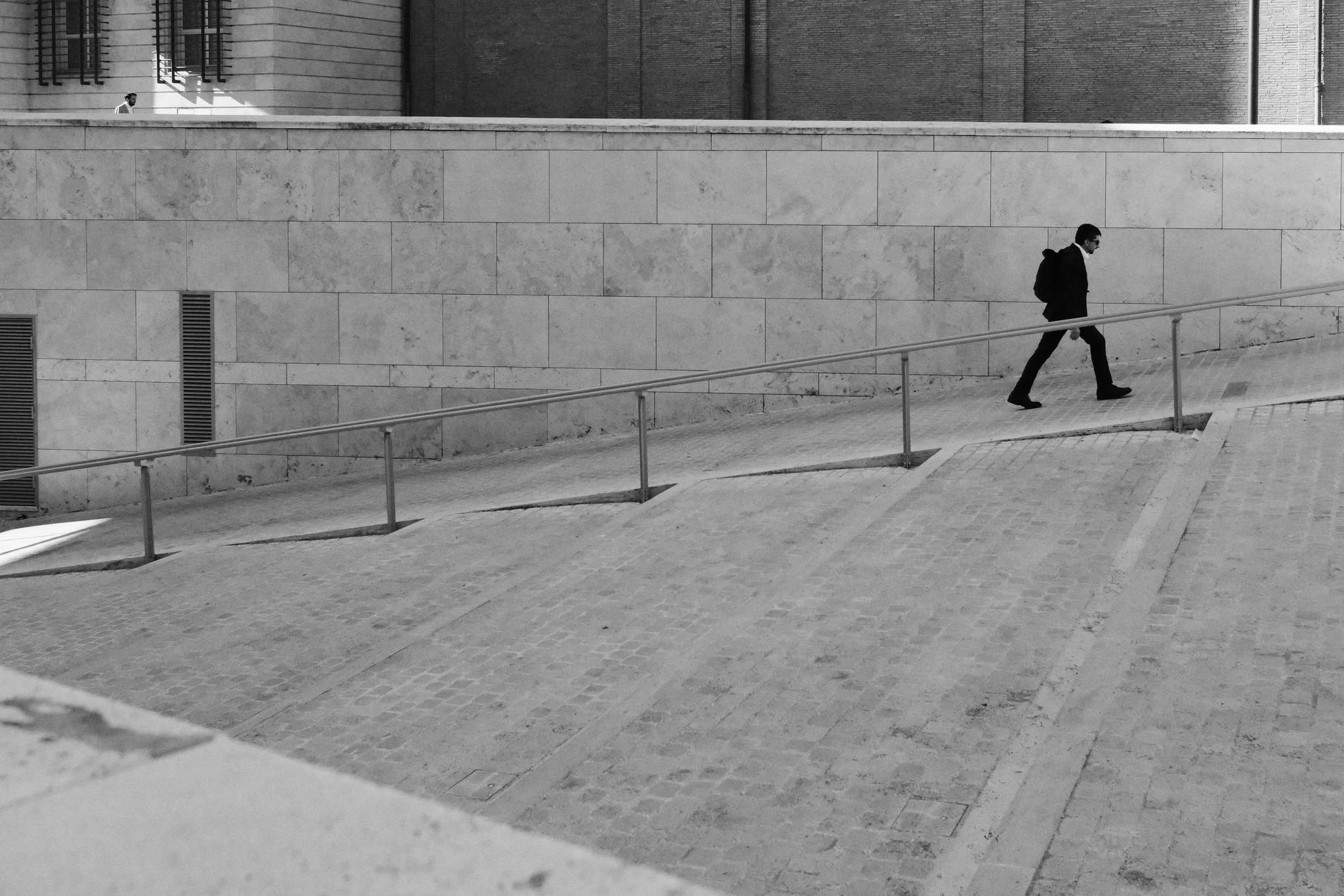 Un uomo percorre una rampa urbana geometrica in bianco e nero