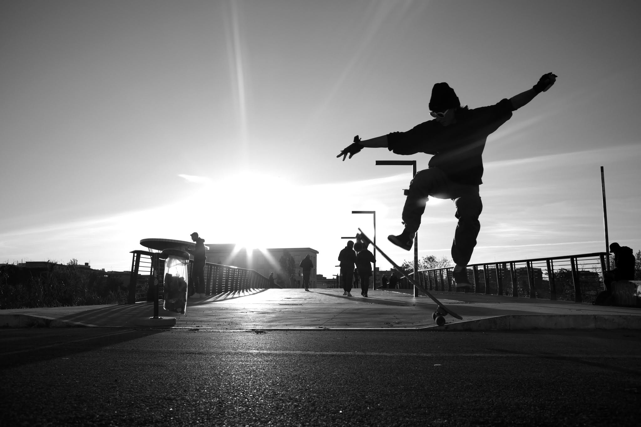 Uno skater salta controluce in una piazza