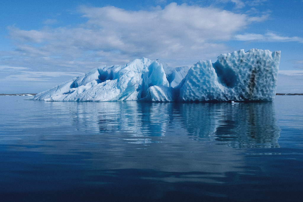 Un grande iceberg azzurro si riflette nell'acqua calma